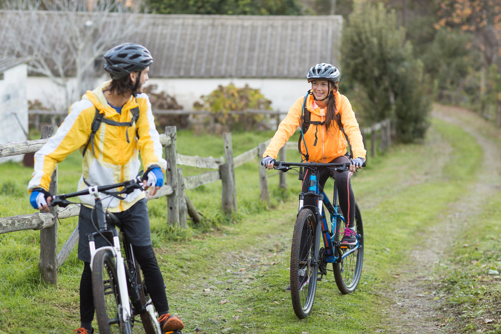 Biker couple interacting while cycling in countryside track